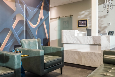 waiting room with a couple of green chairs and modern art on the walls